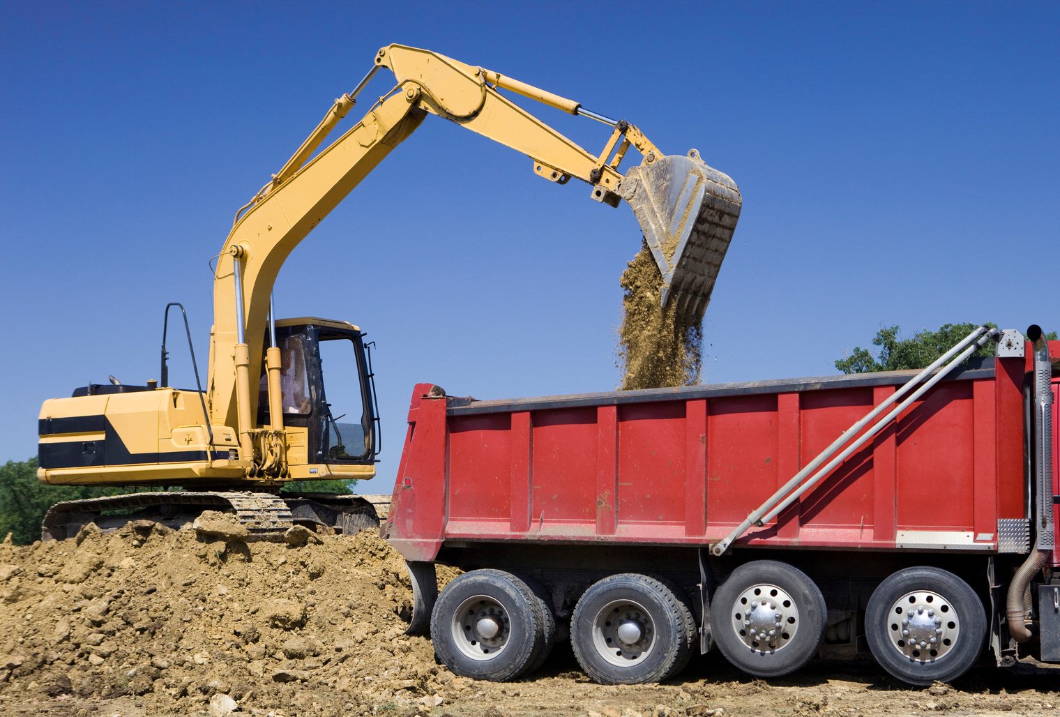 Excavator Dumping Dirt into Dump Truck